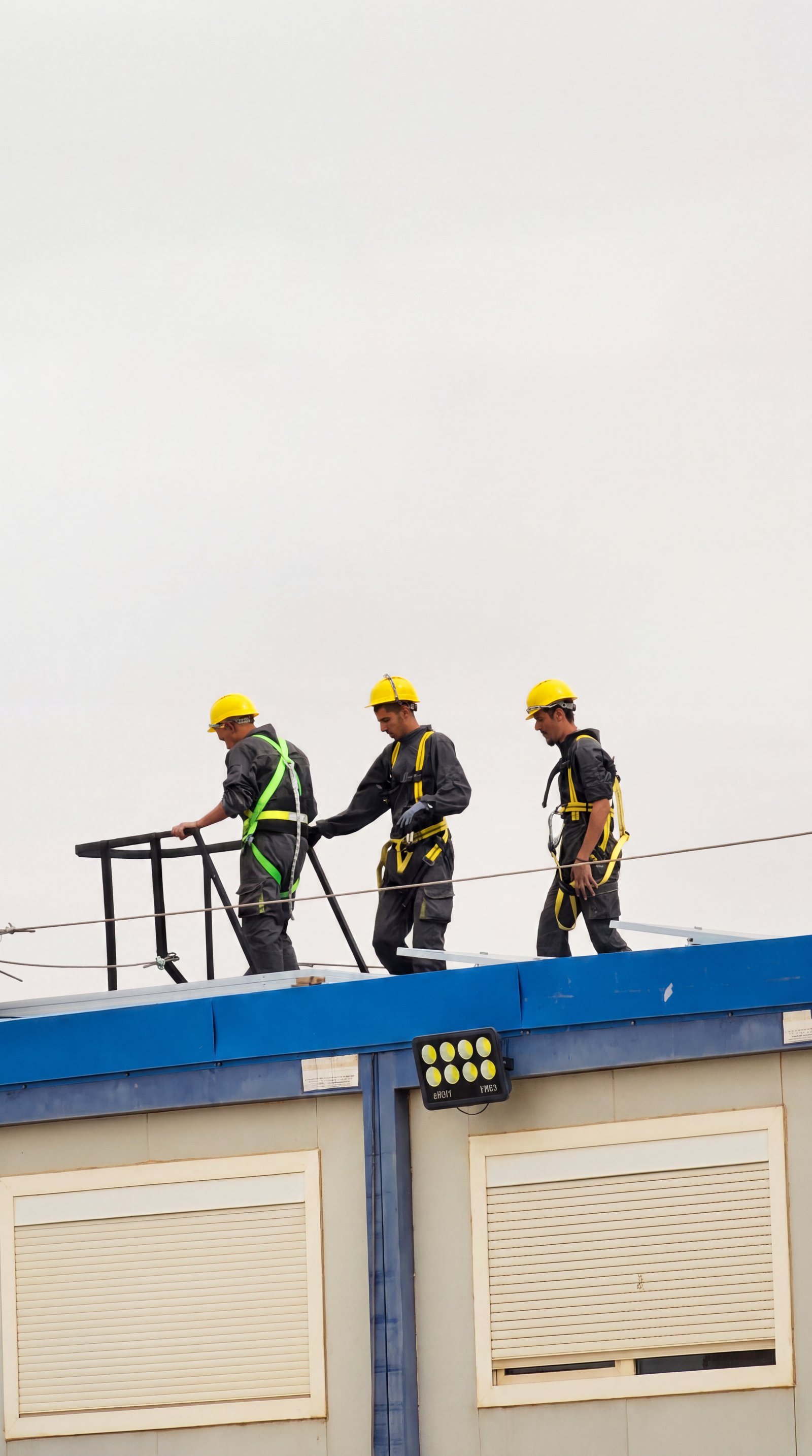 Installation crew in harnesses working a rooftop edge